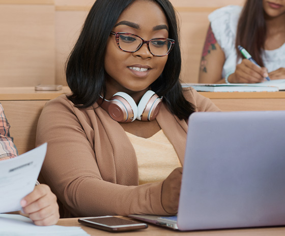 Student reviewing paperwork and a laptop while preparing visa documents
